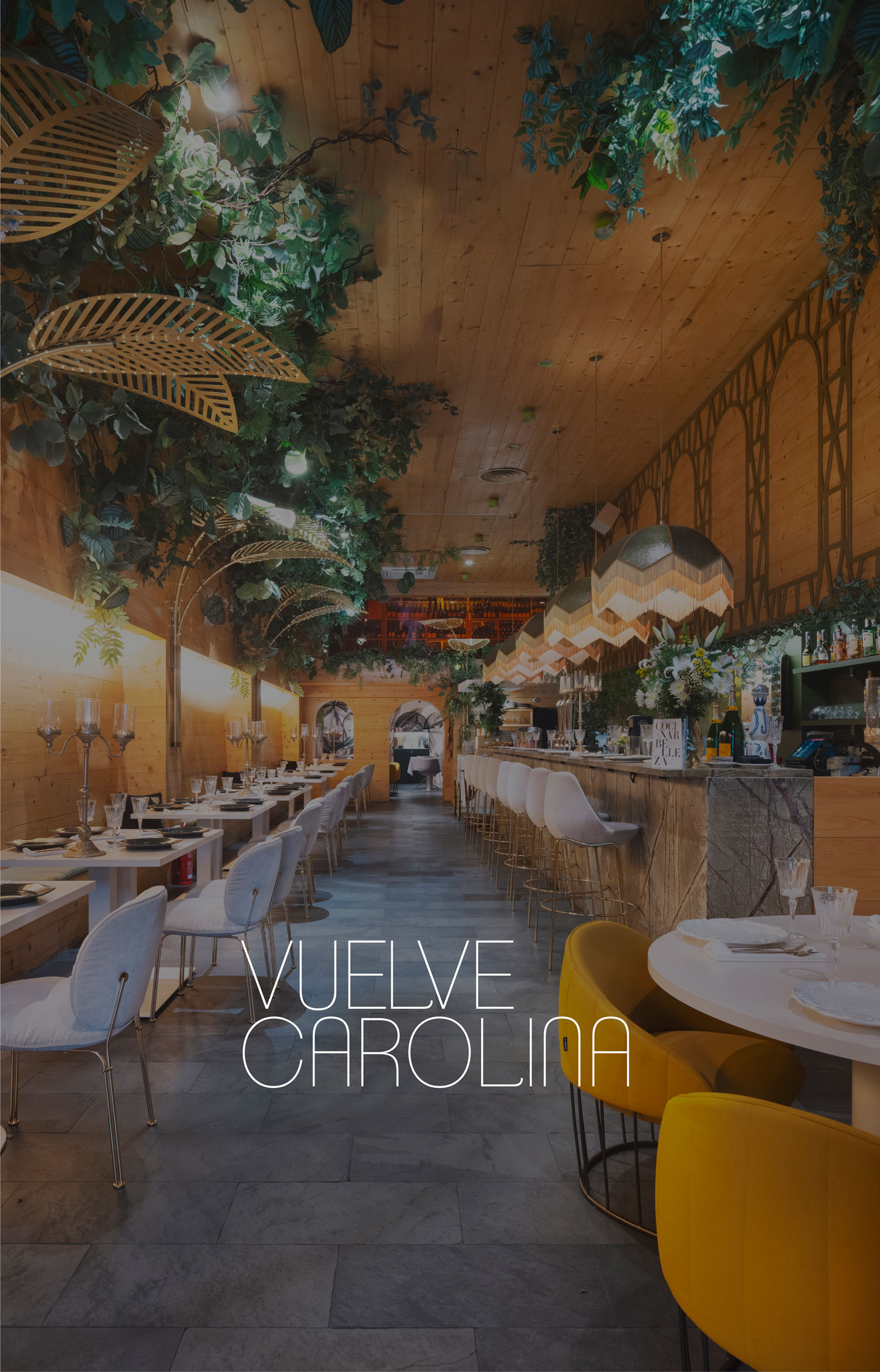 Interior de Vuelve Carolina con barra, mesas y sillas, techo de madera y abundantes plantas colgantes.